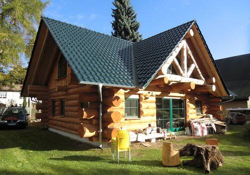 Naturstamm Blockhaus mit Ziegeldach. Die Vorköpfe in "Vor- und Zurück" Variante. Dazu ein tolles Block - Gebinde.