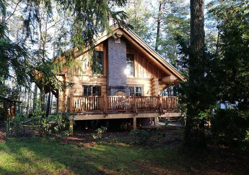 Naturstammhaus "Tucker" - Blick auf Giebel mit Terrasse und Schornstein 